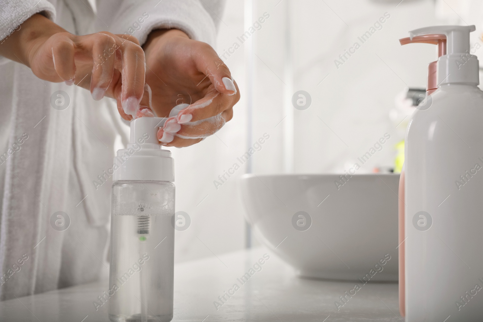 Photo of Teenage girl using cleansing foam in bathroom, closeup. Skin care cosmetic