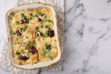 Photo of Tasty sausage casserole in baking dish on white marble table, top view. Space for text