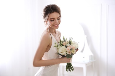 Bride in beautiful wedding dress with bouquet indoors