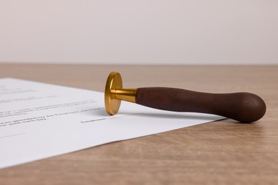 Photo of One stamp tool and document on wooden table, closeup