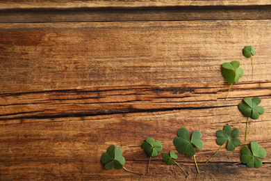 Clover leaves on wooden table, flat lay with space for text. St. Patrick's Day celebration