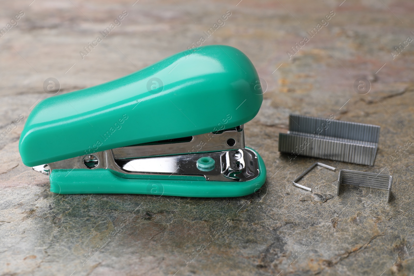 Photo of Turquoise stapler with staples on stone textured surface