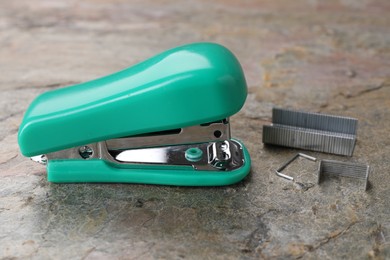 Turquoise stapler with staples on stone textured surface