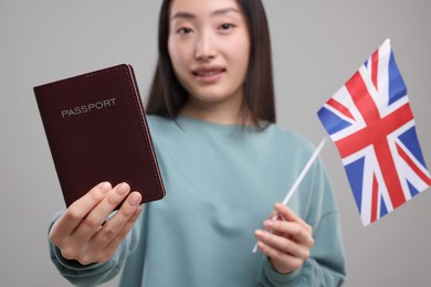 Immigration to United Kingdom. Happy woman with passport and flag on grey background, selective focus