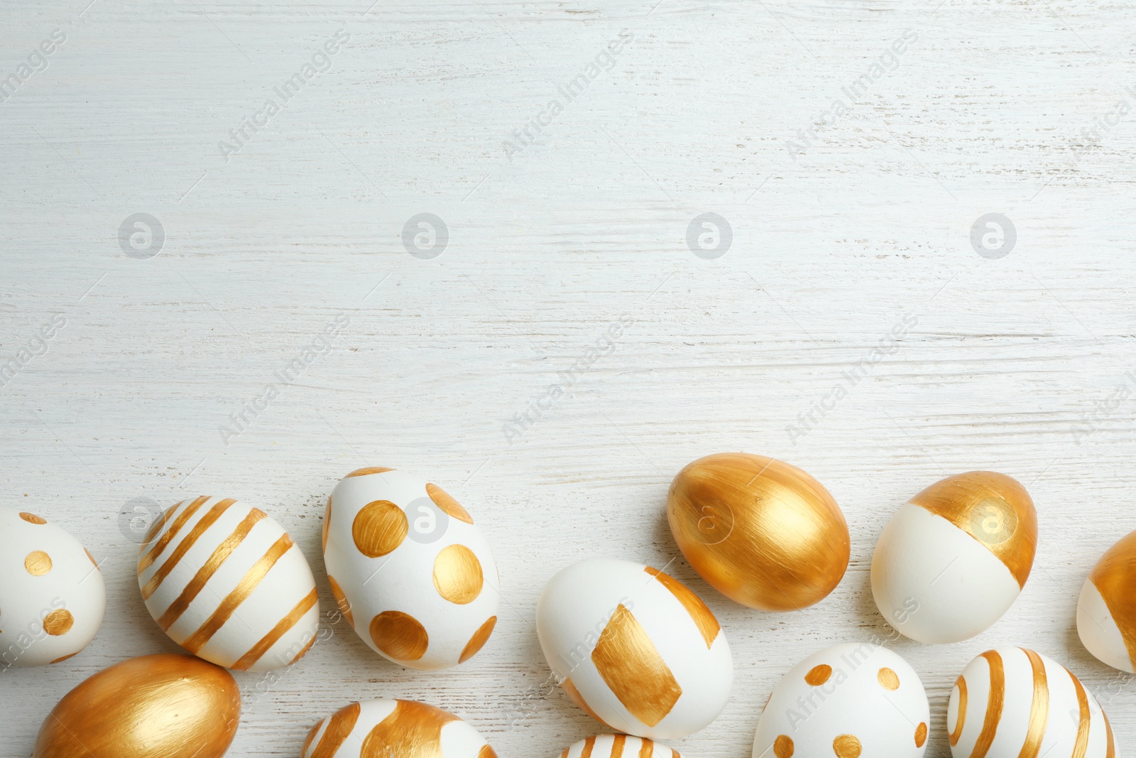 Photo of Traditional Easter eggs decorated with golden paint on wooden background, top view. Space for text