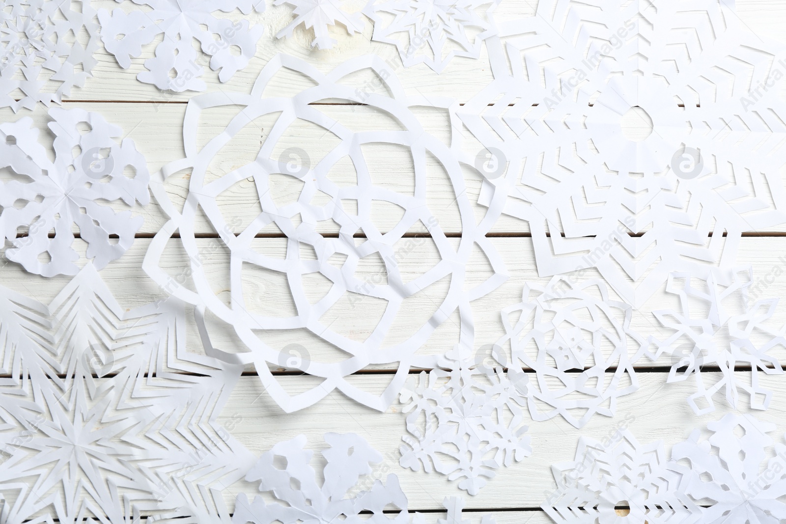 Photo of Many paper snowflakes on white wooden background, flat lay
