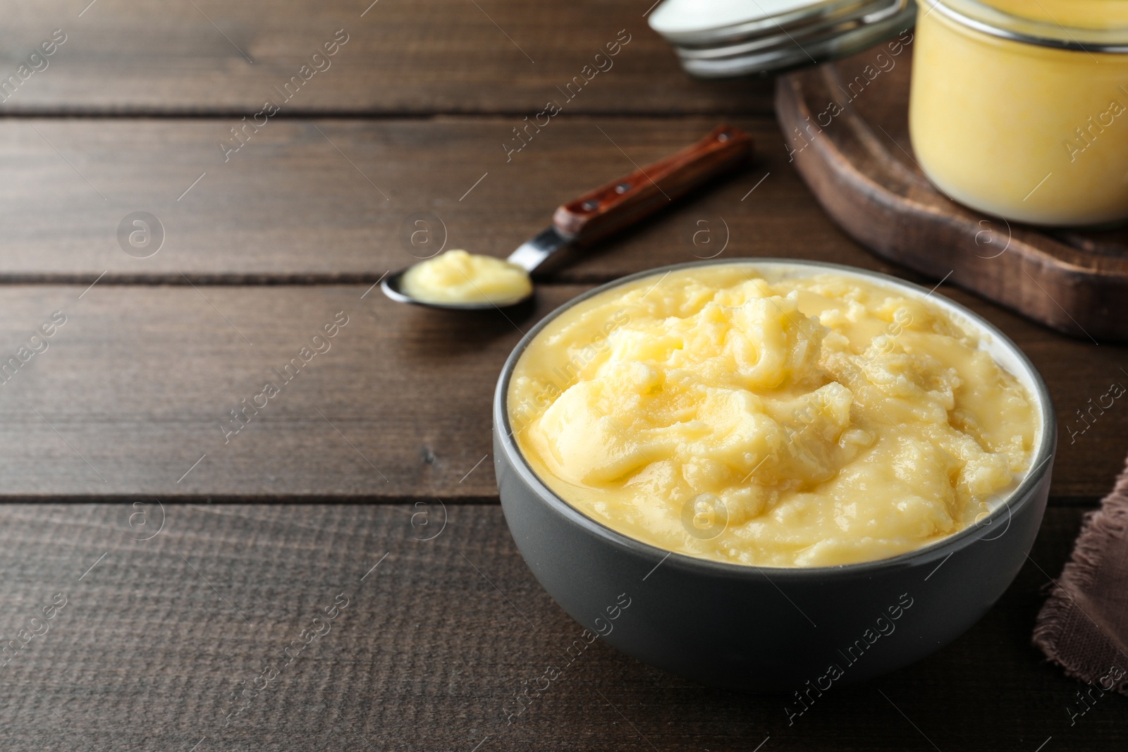 Photo of Bowl of Ghee butter on wooden table. Space for text