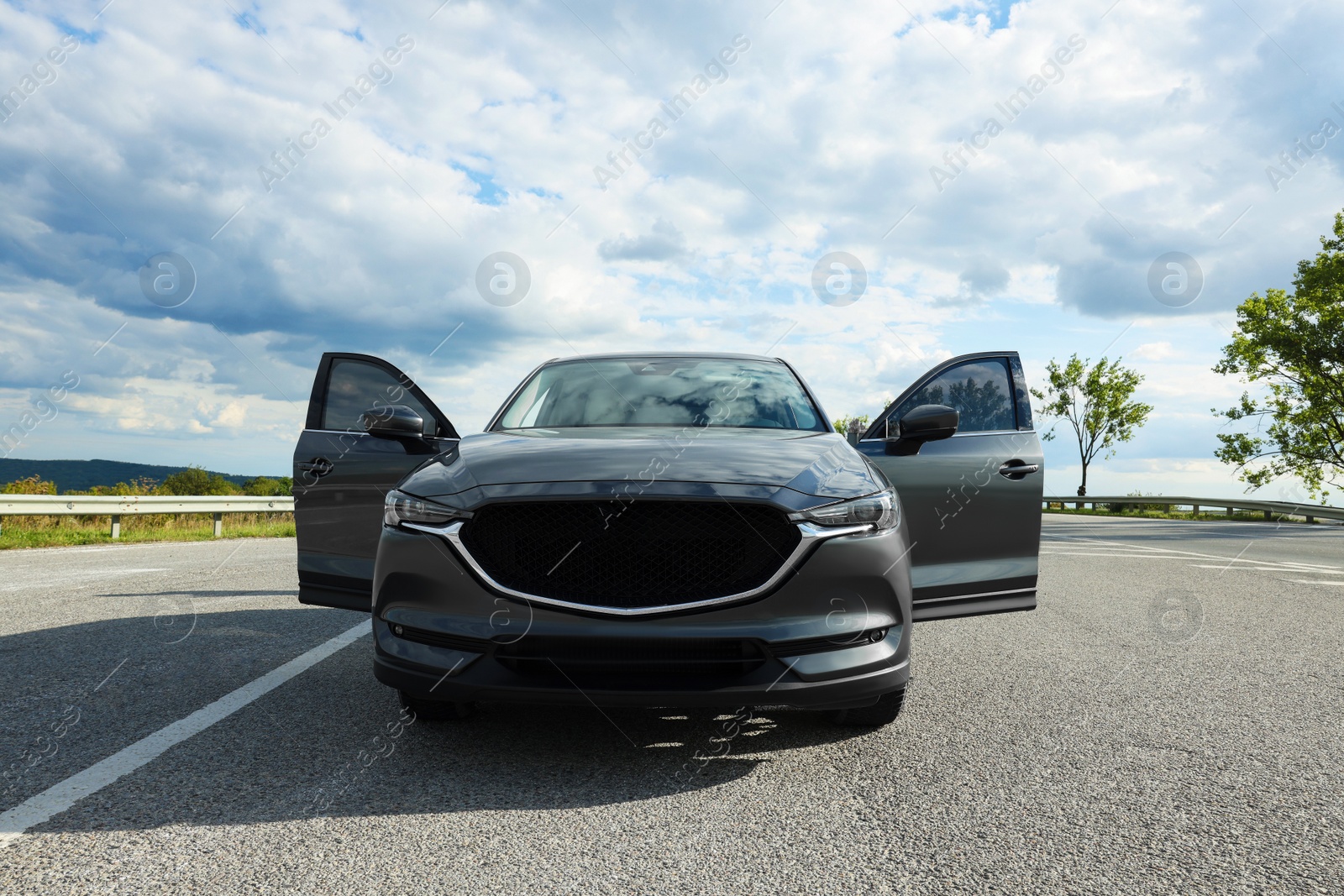 Photo of New black modern car with open doors on asphalt road