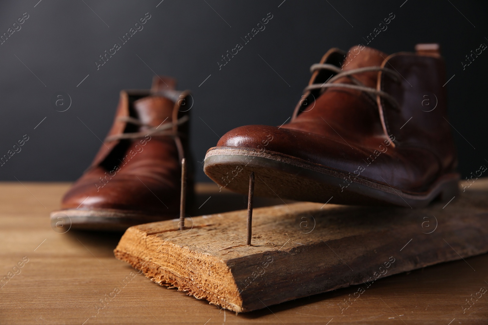 Photo of Metal nails in wooden plank and shoes on table