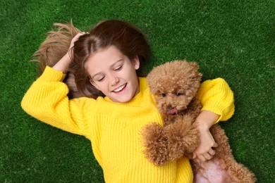 Photo of Little child with cute puppy on green grass, top view. Lovely pet