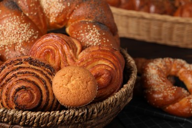Photo of Wicker basket and different tasty freshly baked pastries on table, closeup
