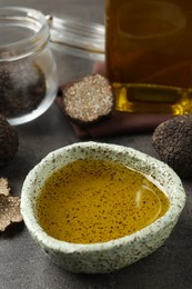 Photo of Fresh truffle oil in bowl on grey table