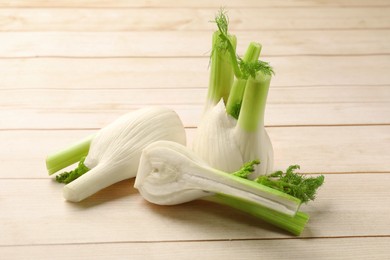 Photo of Fresh raw fennel bulbs on light wooden table