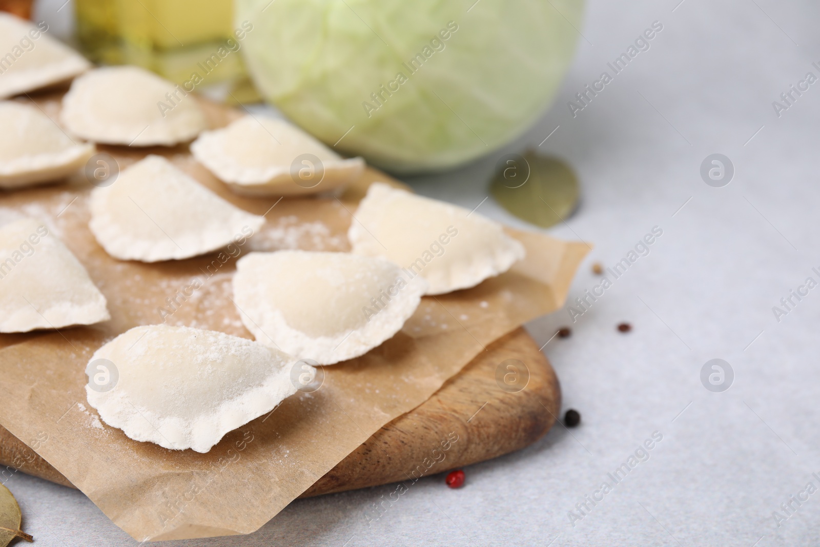 Photo of Raw dumplings (varenyky) with tasty filling on light grey table, closeup. Space for text