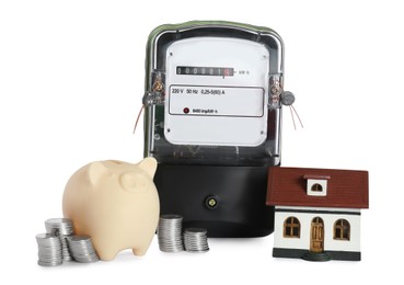 Electricity meter, house model, piggy bank and stacked coins on white background
