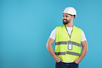 Photo of Engineer with hard hat and badge on light blue background, space for text