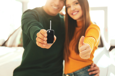 Photo of Happy couple with car key in modern auto dealership, focus on hand