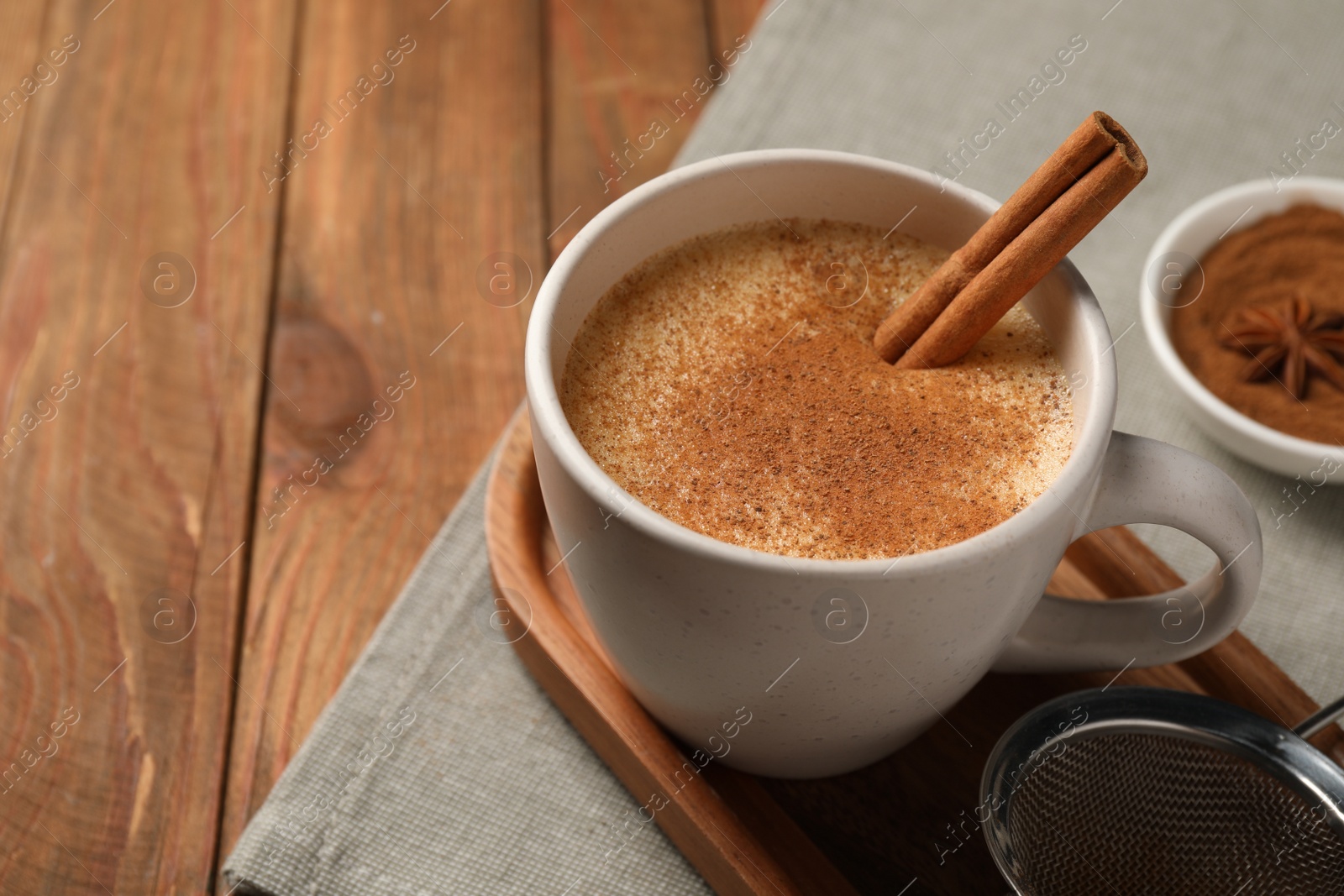 Photo of Delicious eggnog with anise and cinnamon on wooden table, closeup. Space for text