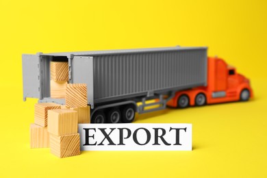 Photo of Toy truck and wooden cubes on yellow background. Export concept