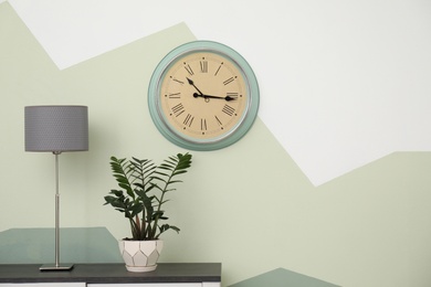 Photo of Big clock hanging on color wall. Time concept