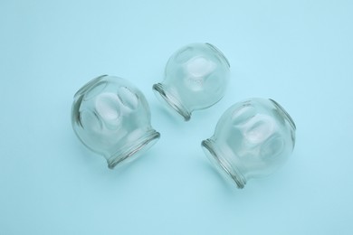 Photo of Glass cups on light blue background, flat lay. Cupping therapy