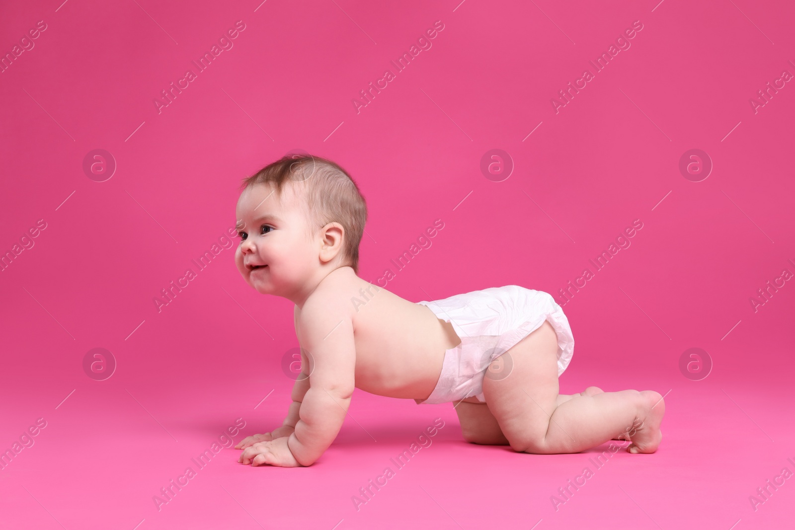 Photo of Cute little baby in diaper crawling on pink background