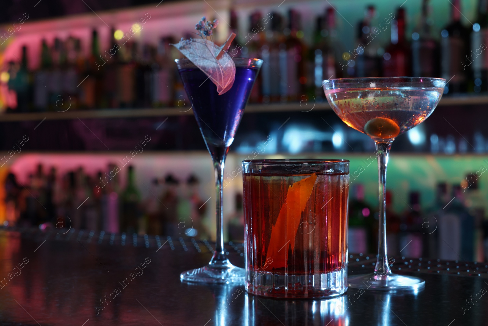 Photo of Different fresh alcoholic cocktails on counter in bar. Space for text