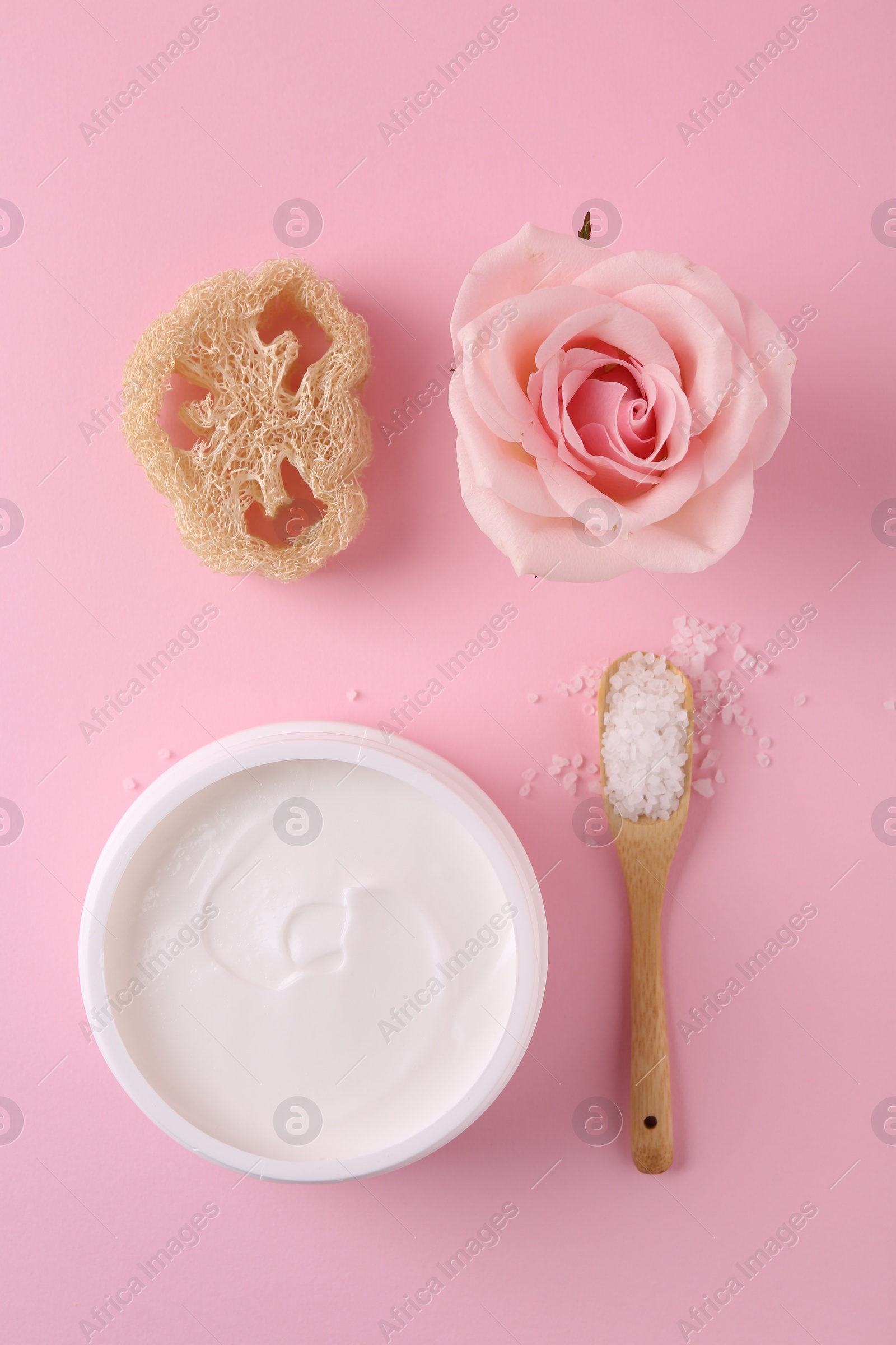 Photo of Jar of cream, sea salt and loofah on pink background, flat lay. Body care products