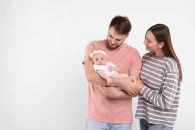 Photo of Happy family. Parents with their cute baby on light background, space for text