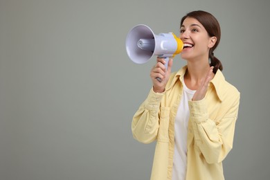 Special promotion. Young woman shouting in megaphone on grey background, space for text