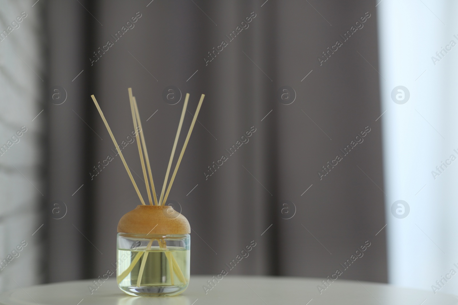 Photo of Aromatic reed air freshener on table indoors. Space for text