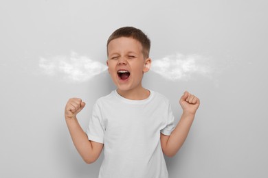 Image of Aggressive little boy with steam coming out of his ears on grey background