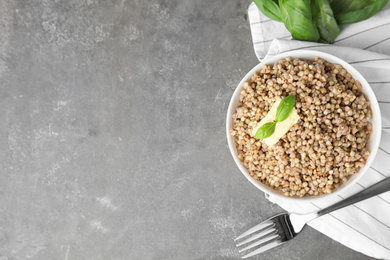 Tasty buckwheat porridge with butter on grey table, flat lay. Space for text