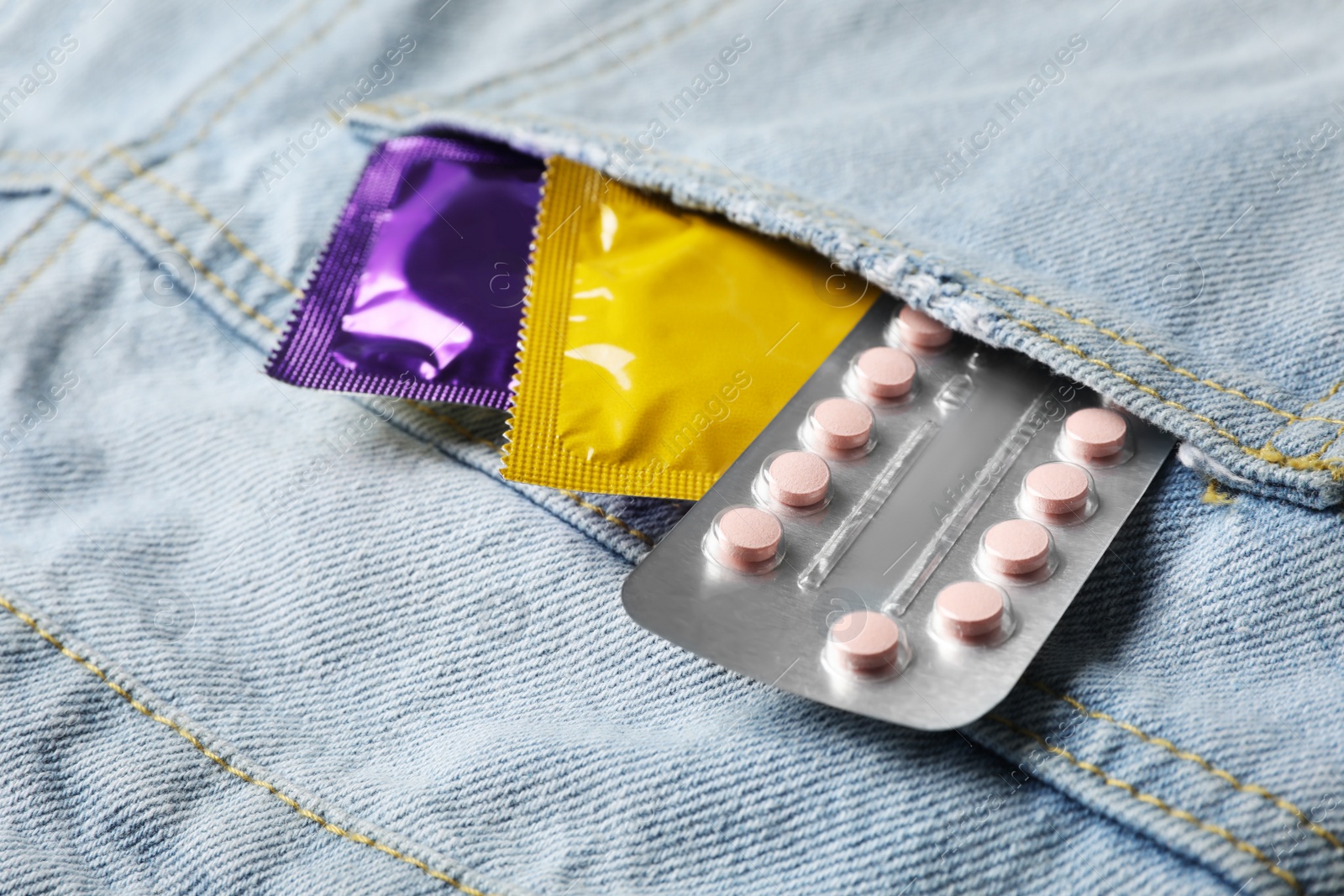 Photo of Condoms and birth control pills in pocket of jeans, closeup. Safe sex concept