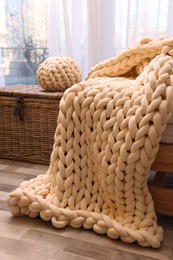 Beautiful knitted blanket and pillow near window in room