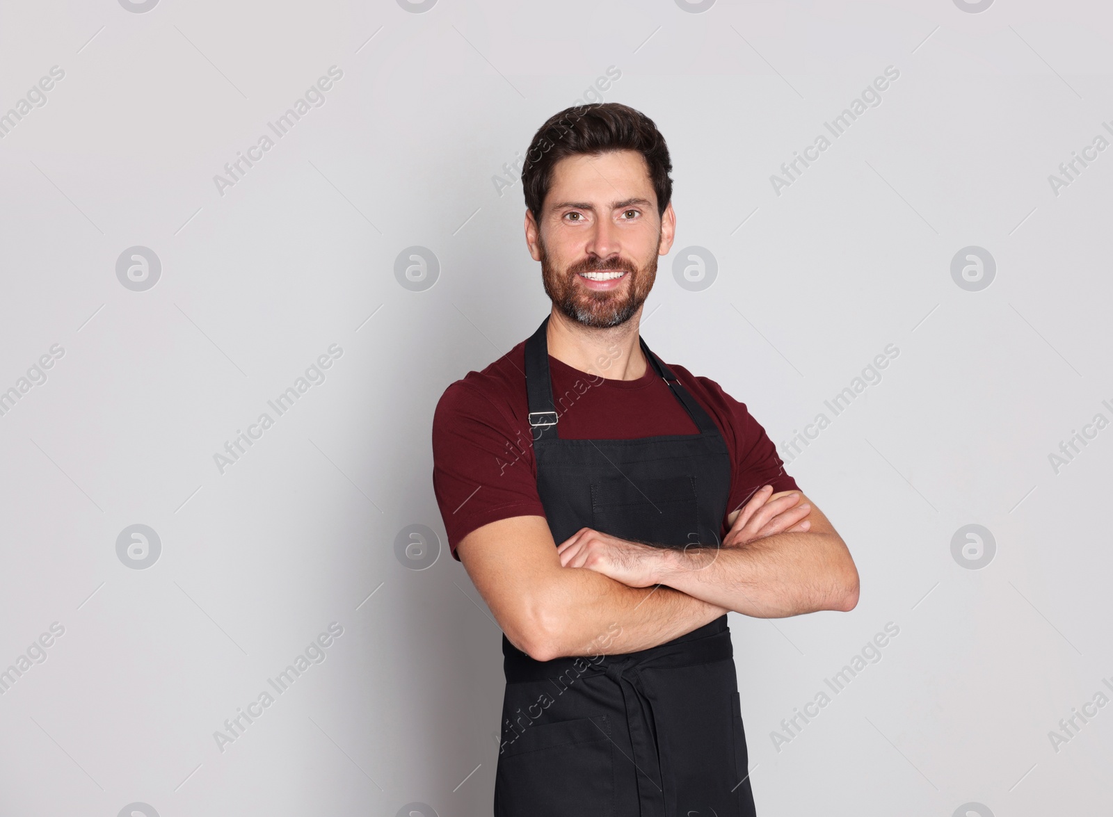 Photo of Professional hairdresser wearing apron with on light grey background, space for text