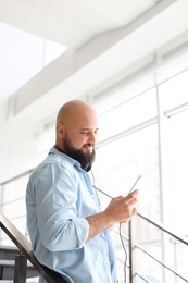 Portrait of young man with mobile phone and headphones on stairs