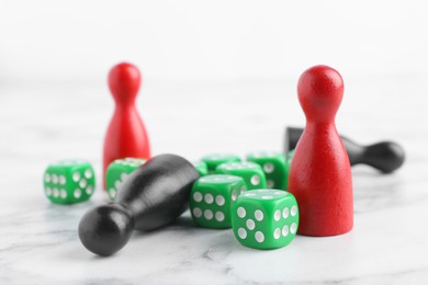Photo of Green dices and color game pieces on white marble table, closeup