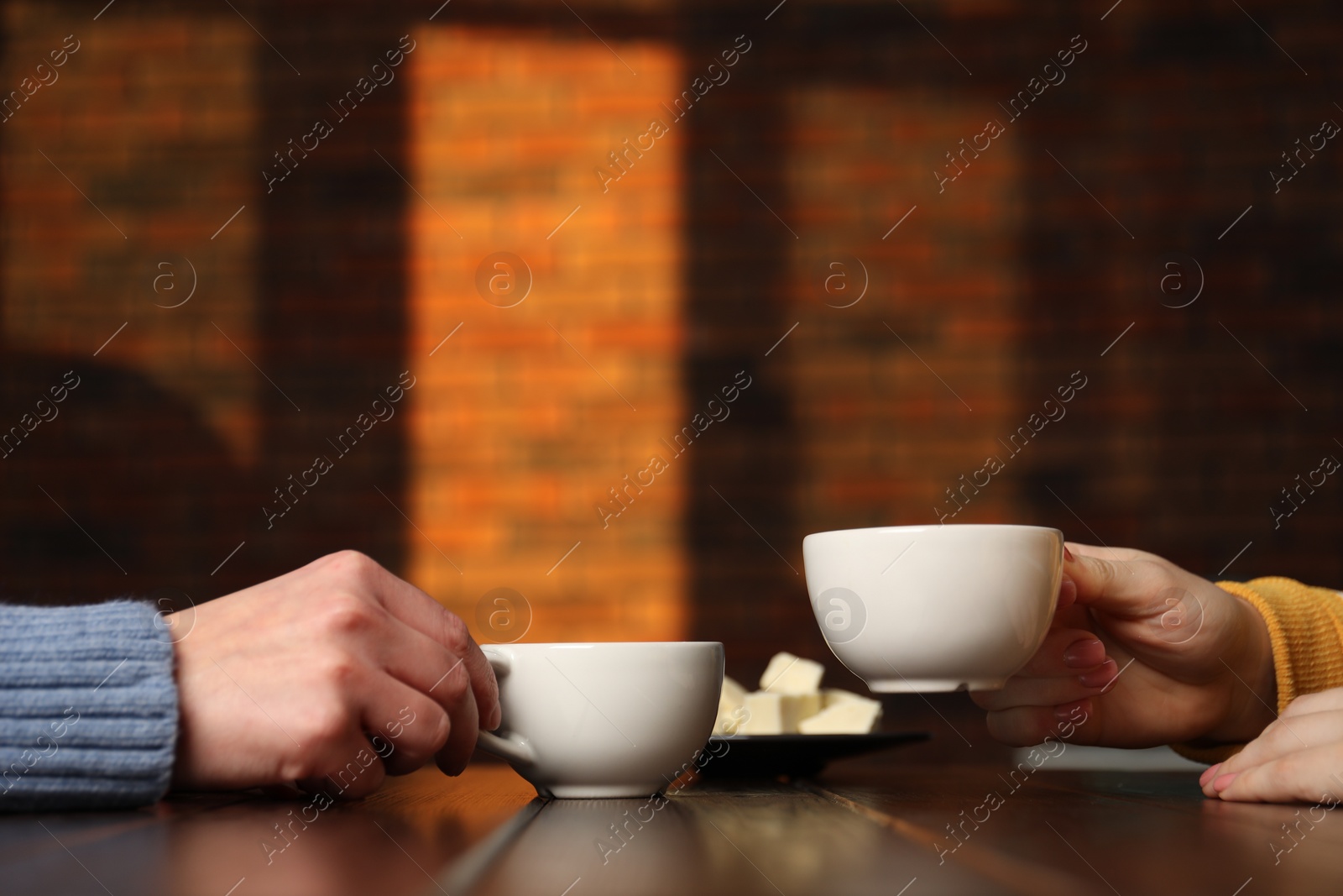 Photo of Women having coffee break at wooden table in cafe, closeup