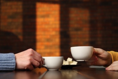 Photo of Women having coffee break at wooden table in cafe, closeup