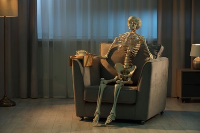 Photo of Waiting concept. Human skeleton sitting in armchair indoors