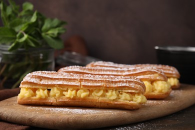 Photo of Delicious eclairs filled with cream on wooden table