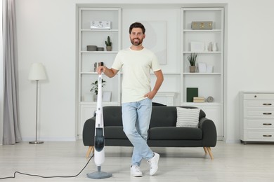 Happy man with steam mop at home