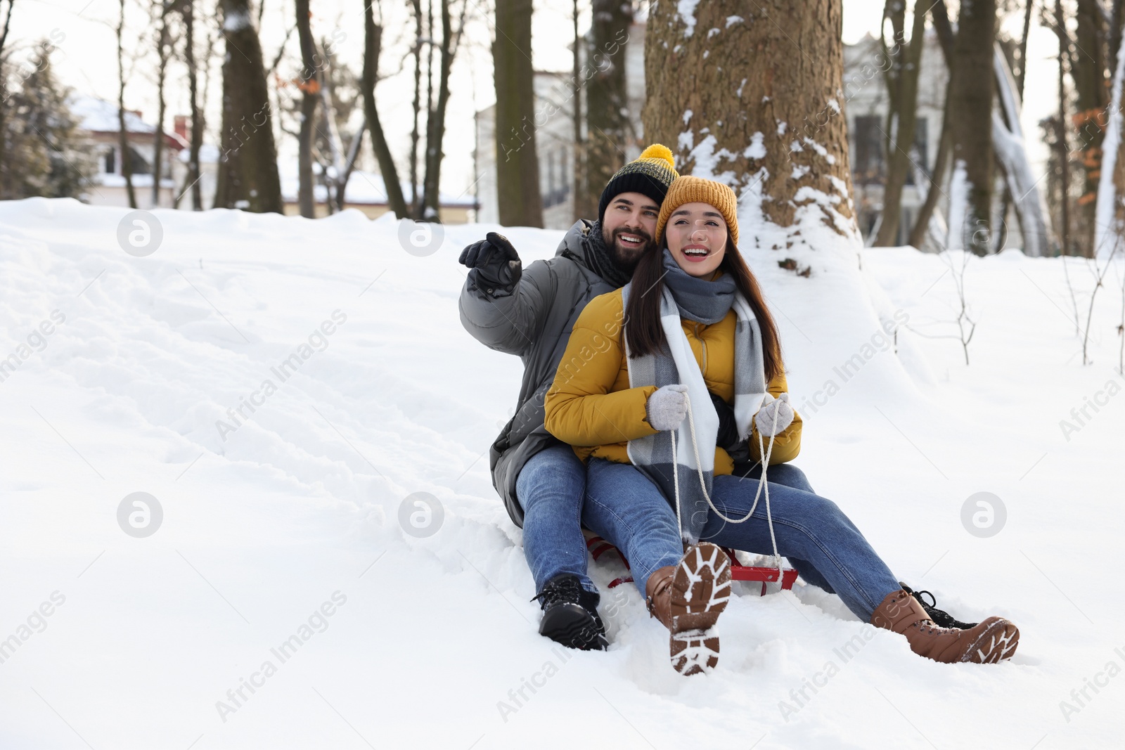 Photo of Happy young couple sledding outdoors on winter day