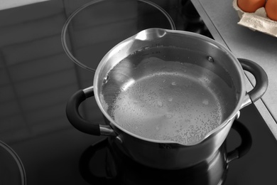 Photo of Pot with boiling water on electric stove in kitchen, space for text