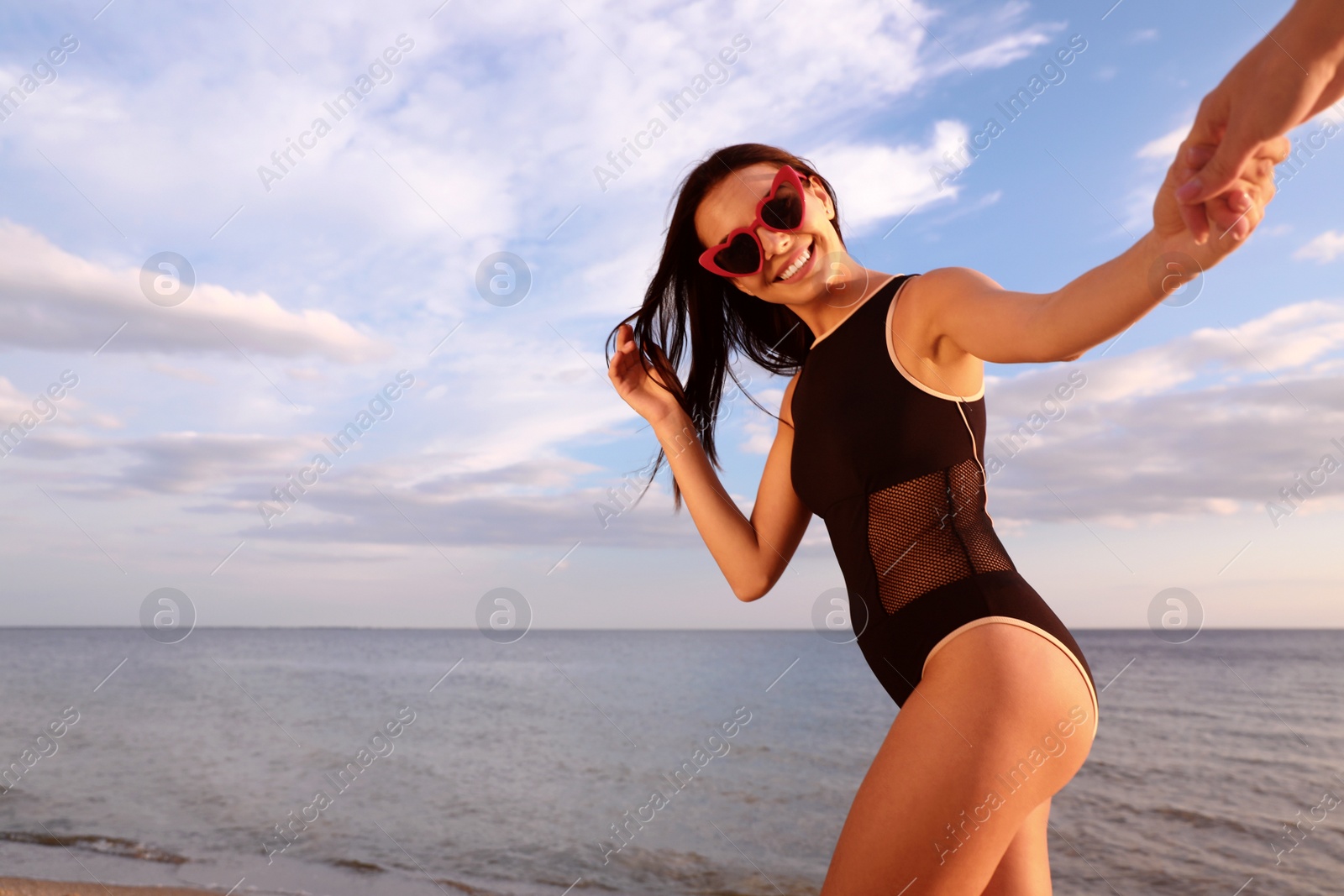 Photo of Young woman holding hands with girlfriend on beach