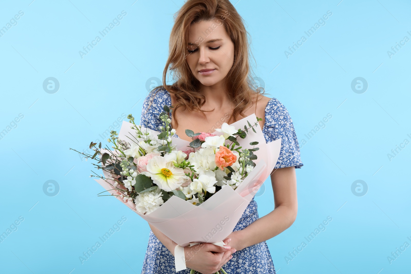 Photo of Beautiful woman with bouquet of flowers on light blue background