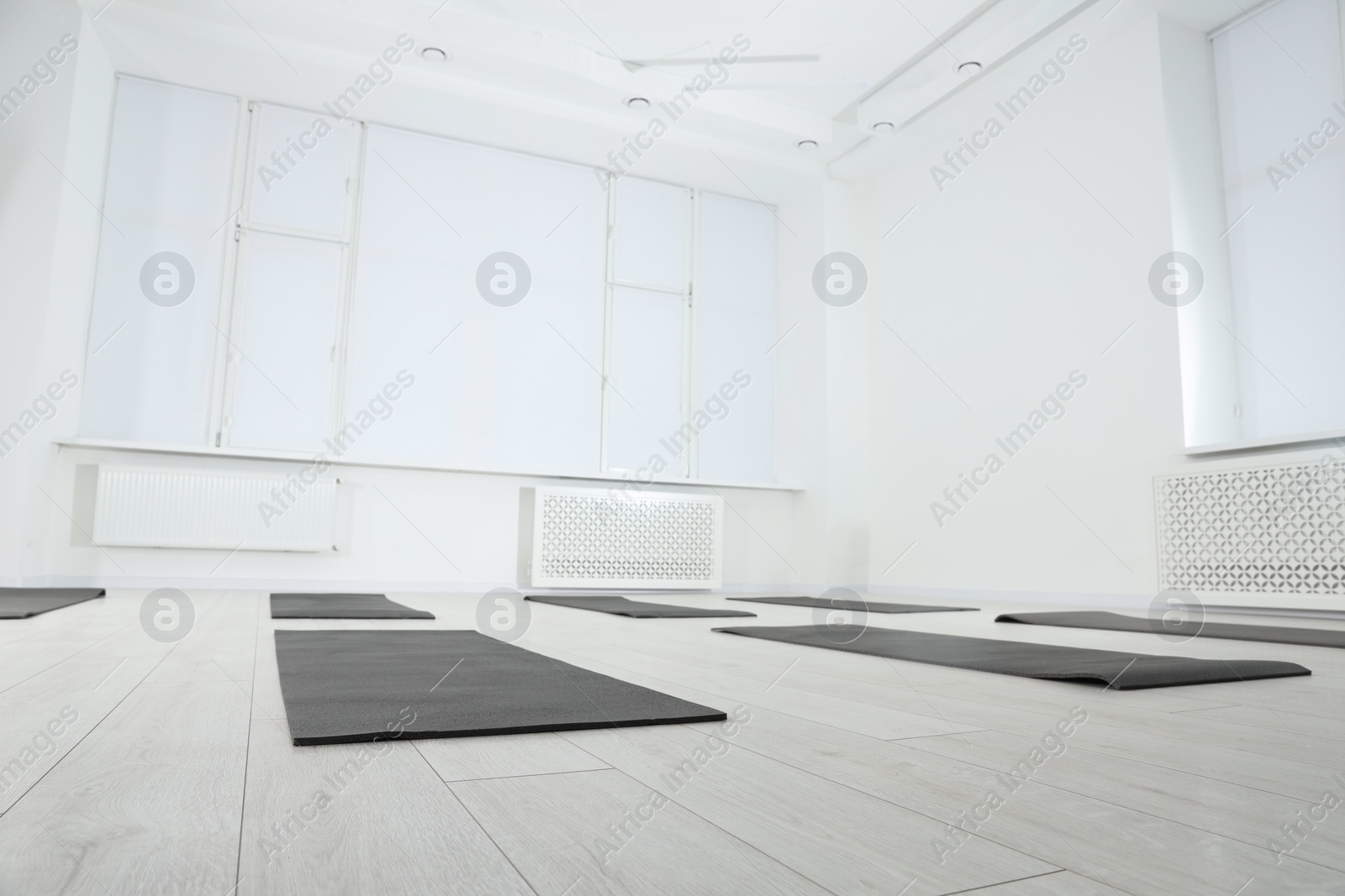 Photo of Spacious yoga studio with exercise mats and big windows, low angle view