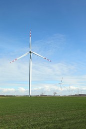 Modern wind turbines in field on sunny day. Alternative energy source