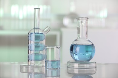 Laboratory analysis. Different glassware with liquid on white table against blurred background